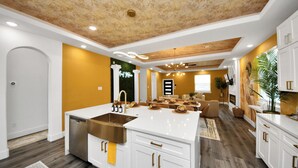 Una cocina moderna con una isla central, armarios blancos y techo de madera.