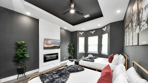 Un dormitorio moderno con una cama grande, televisión y ventilador de techo.