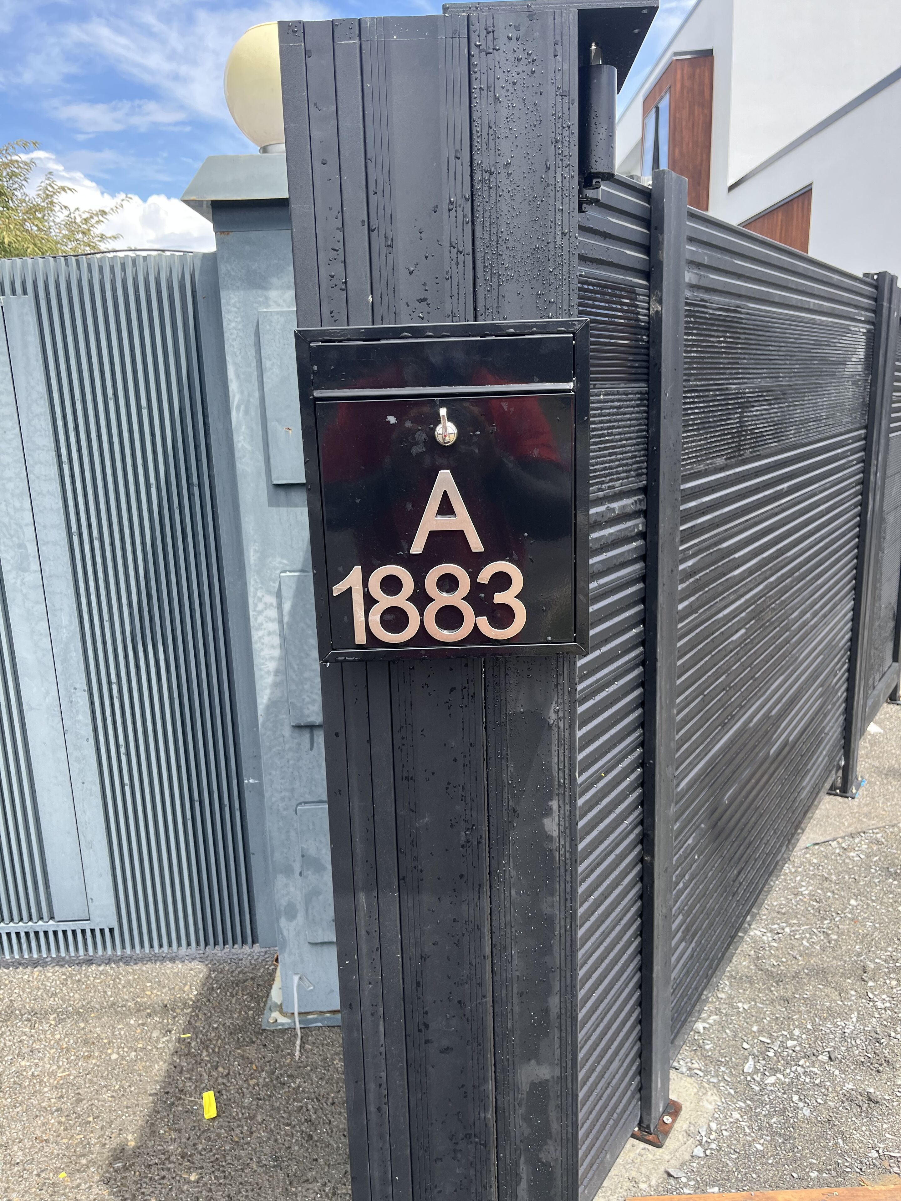 A black mailbox with a house number 'A 1883' on a metal post.