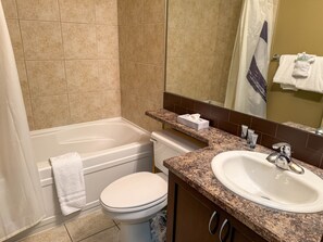 Une salle de bain équipée d’une baignoire, de toilettes, d’un lavabo et d’un miroir.