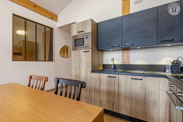 Une cuisine compacte avec des meubles en bois, un four à micro-ondes, un évier et une table à manger avec des chaises.