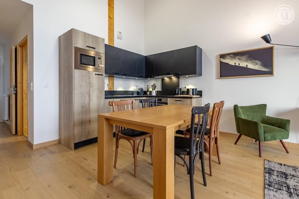 Una cocina moderna con armarios oscuros, una mesa de comedor de madera y sillas.