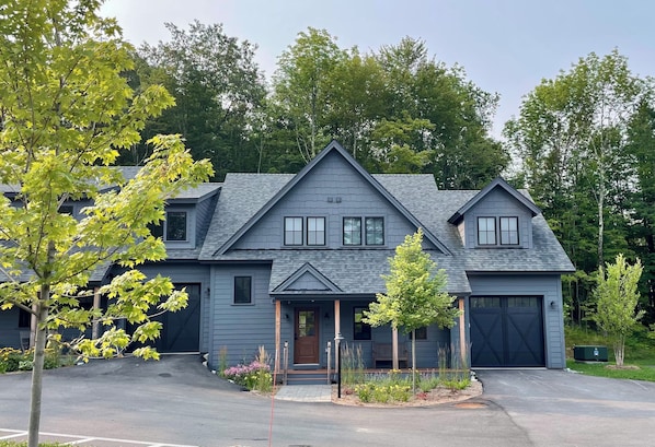 A two-story house with a dark gray exterior, a front porch, and a garage.