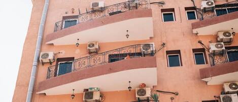 A multi-story building with balconies, air conditioning units, and a simple architectural design.