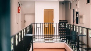 A staircase with a wooden door at the top, a fire extinguisher on the wall, and a railing with decorative elements. - Hotel Appart Larabi (Marrakech)