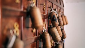 A close-up of a wooden wall with numbered locks and keys, suggesting a secure storage area. - Hotel Appart Larabi (Marrakech)