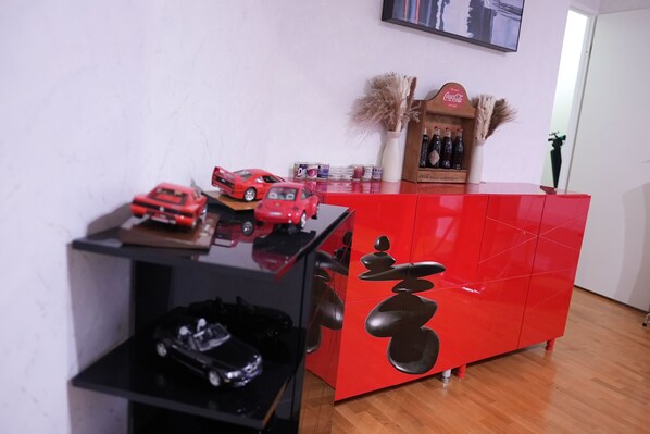 A red cabinet with a glass shelf displaying toy cars.