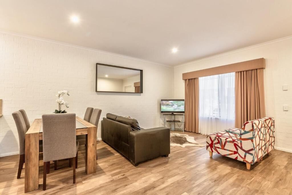 A modern living room with a dining table, sofa, and TV.