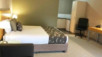Una habitación de hotel con cama, escritorio, silla y armario.