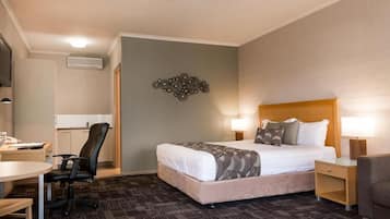 Habitación de hotel con cama, escritorio, silla y un adorno de pared.
