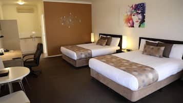 A hotel room with two beds, a desk, and a chair.