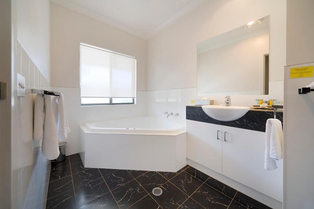 A modern bathroom with a bathtub, a large mirror, and a vanity with a sink.