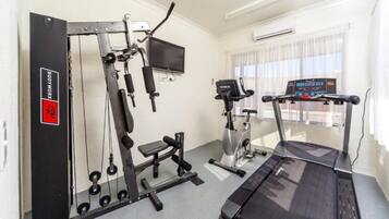 Une salle de sport équipée de machines de cardio, d’un banc de musculation et d’un tapis de course.