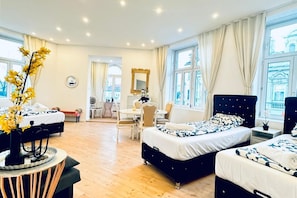 Ett hotellrum med två sängar, ett skrivbord, en stol och stora fönster.