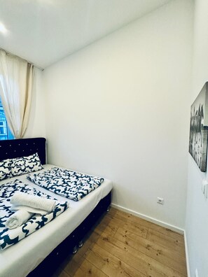A bedroom with a bed, a headboard, a window with curtains, a wooden floor, and a wall-mounted picture. - Private Room; Just 11 Min Walk to Atzgersdorf Park (Wien)