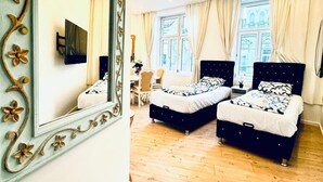 Een slaapkamer met twee bedden, een televisie, een spiegel en een raam met gordijnen.