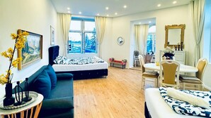 Een hotelkamer met een bed, een bank, een eettafel met stoelen, een spiegel en uitzicht.