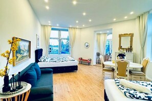 Une chambre d’hôtel moderne équipée d’un lit, d’un canapé, d’un coin repas et offrant une vue sur le paysage urbain.