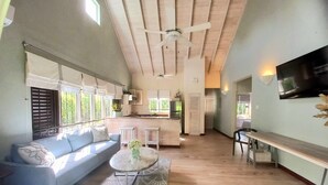 Amplia sala de estar con techo alto, cocina integrada y una zona de asientos con sofá y mesa de centro.