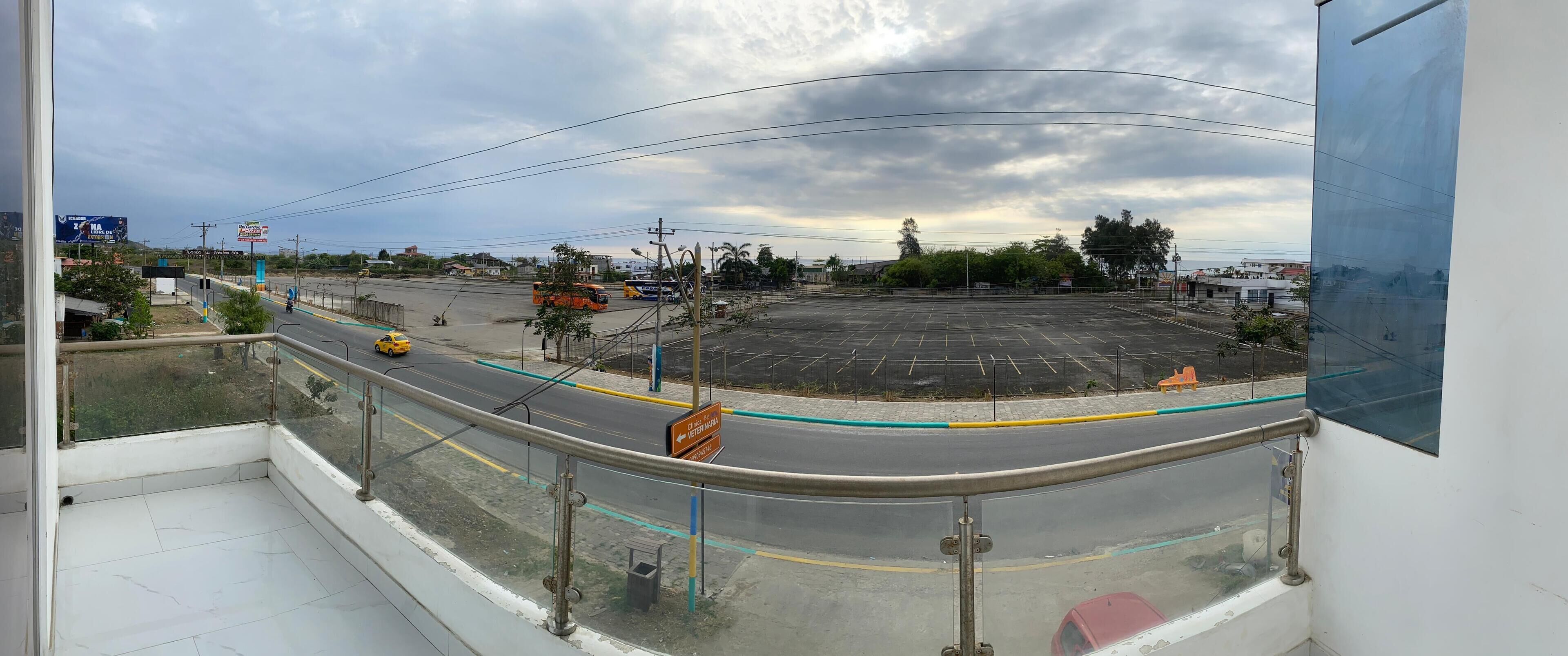 A view from a balcony overlooking a parking lot with a yellow taxi, a bus, and a veterinarian clinic sign.