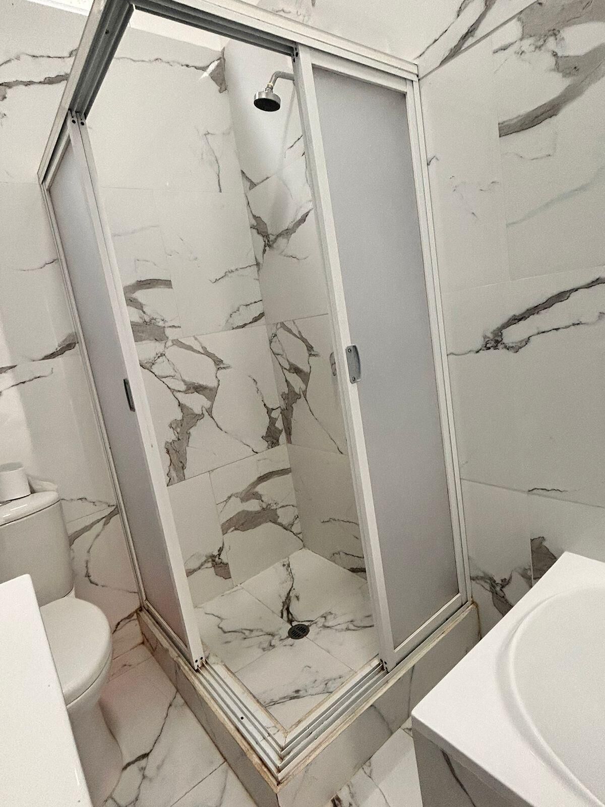 Un baño con cabina de ducha, inodoro y lavabo.