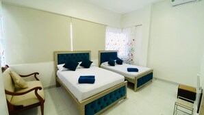 A hotel room with two beds, a chair, and a small table.