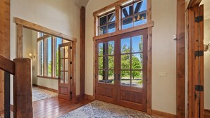 A wooden door with glass panels, a patterned rug, and a view of greenery outside. - Rustic 8B Estate on 40 acres – 9,900sqft Estate on Private Ranch with 2 Hot Tubs (Heber City)
