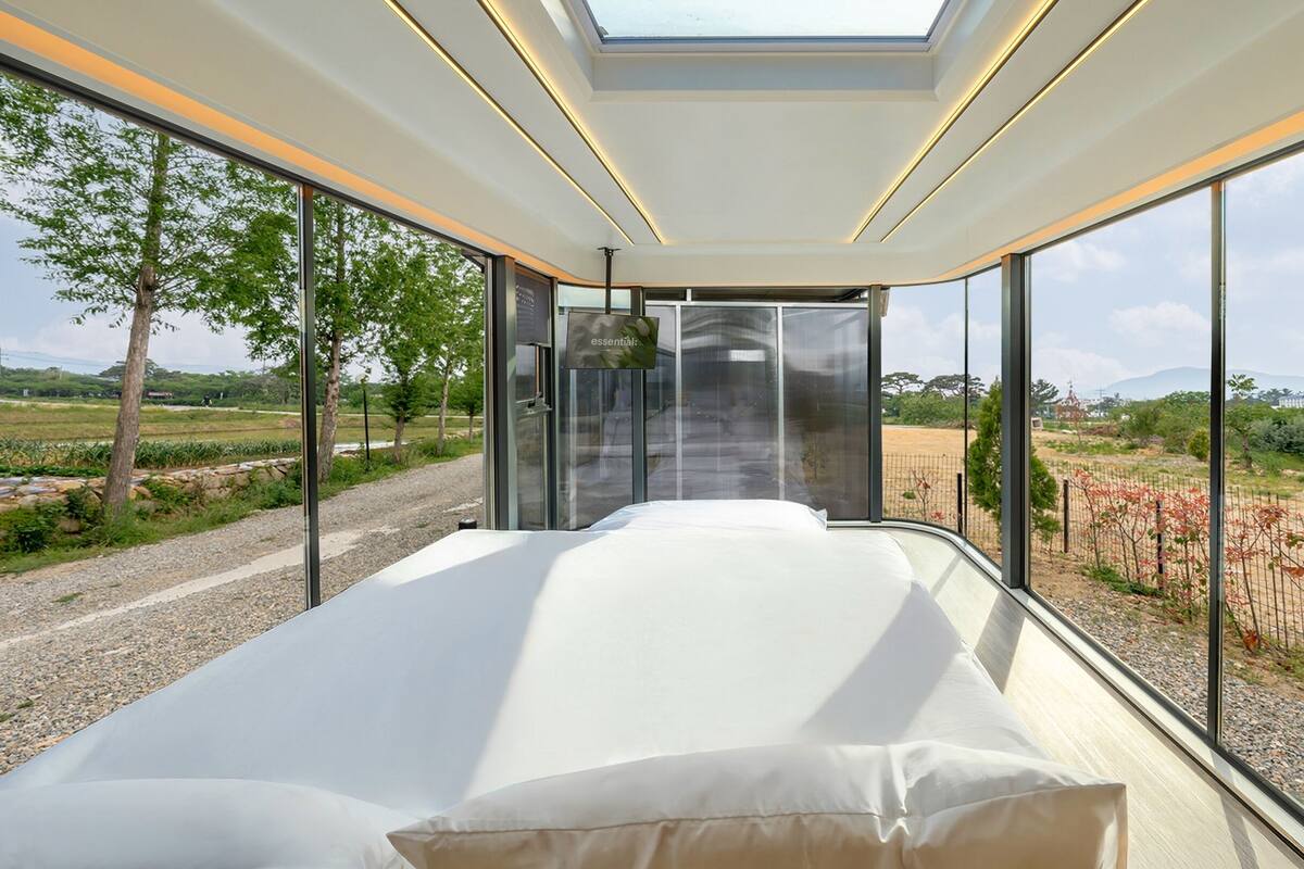 Una habitación moderna con una cama, ventanas amplias y un tragaluz.