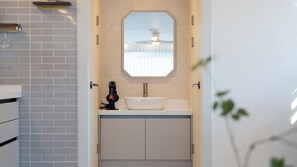 Un baño con un lavamanos blanco, un espejo encima y un ventilador de techo.