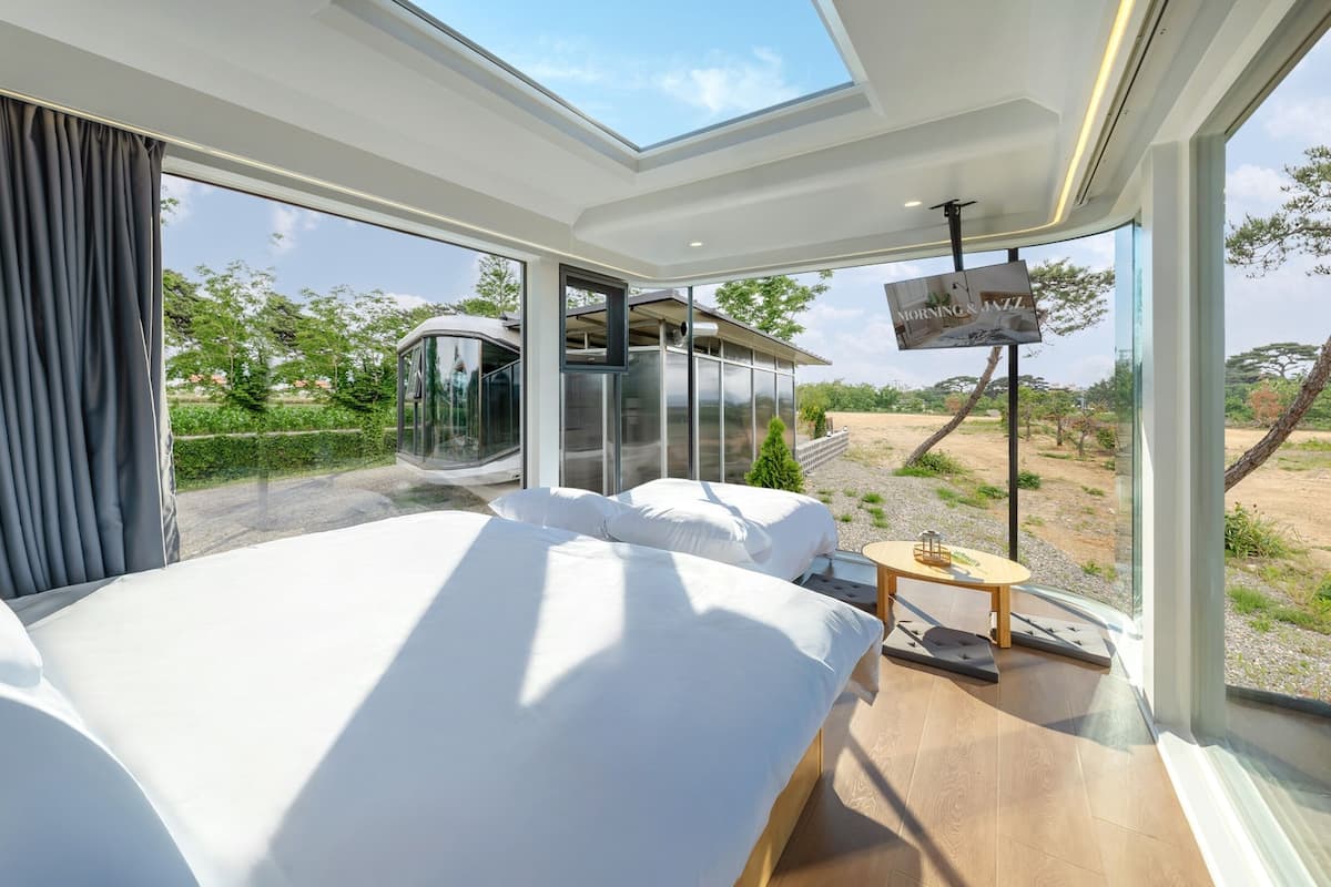 Un dormitorio moderno con una cama grande, un tragaluz y vistas a un edificio y un paisaje.