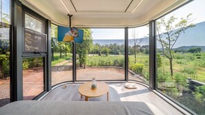 Un intérieur moderne avec de grandes fenêtres, une table ronde et une vue sur un paysage verdoyant.
