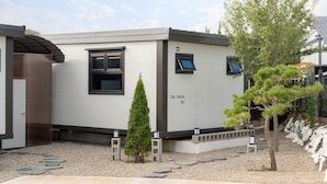 Un edificio moderno identificado como “THE ORION B2”, con un diseño minimalista, que presenta un ventanal y una puerta.