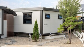 Un edificio moderno identificado como “THE ORION B2”, con un diseño minimalista, que presenta un ventanal y una puerta.