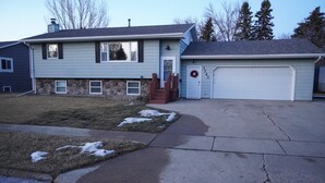 A two-story house with a garage, stone foundation, and a front yard with patches of snow. - Charming 4-bedroom house with WiFi and gaming table in delightful Aberdeen (Aberdeen)