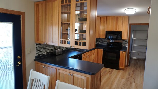 A kitchen with wooden cabinets, a black countertop, a microwave, and a refrigerator. - Charming 4-bedroom house with WiFi and gaming table in delightful Aberdeen (Aberdeen)