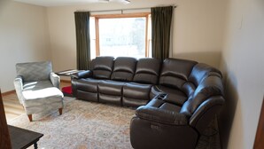 A living room with a sectional sofa, a small armchair, and a coffee table. - Charming 4-bedroom house with WiFi and gaming table in delightful Aberdeen (Aberdeen)
