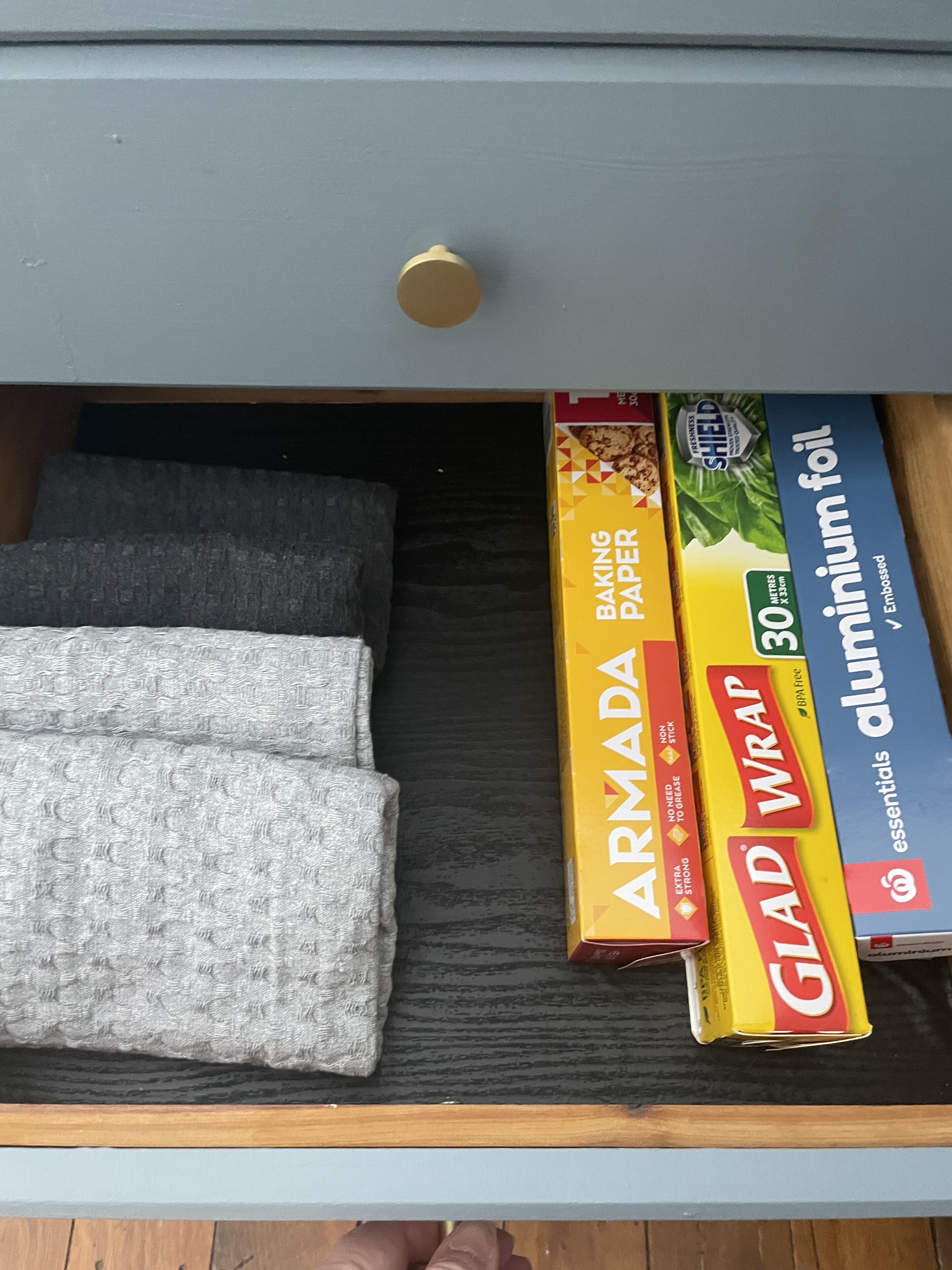 Un tiroir contenant du papier sulfurisé, du papier d’aluminium et une boîte de film alimentaire de la marque Glad Wrap.