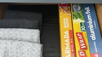 Un tiroir contenant du papier sulfurisé, du papier d’aluminium et une boîte de film alimentaire de la marque Glad Wrap.