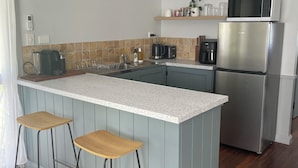 A modern kitchen with a central island, bar stools, a stainless steel refrigerator, a microwave, and a coffee maker. - Country Cottage with Valley Views, 15mins to Canungra, 30mins to Mt Tamborine (Illinbah)