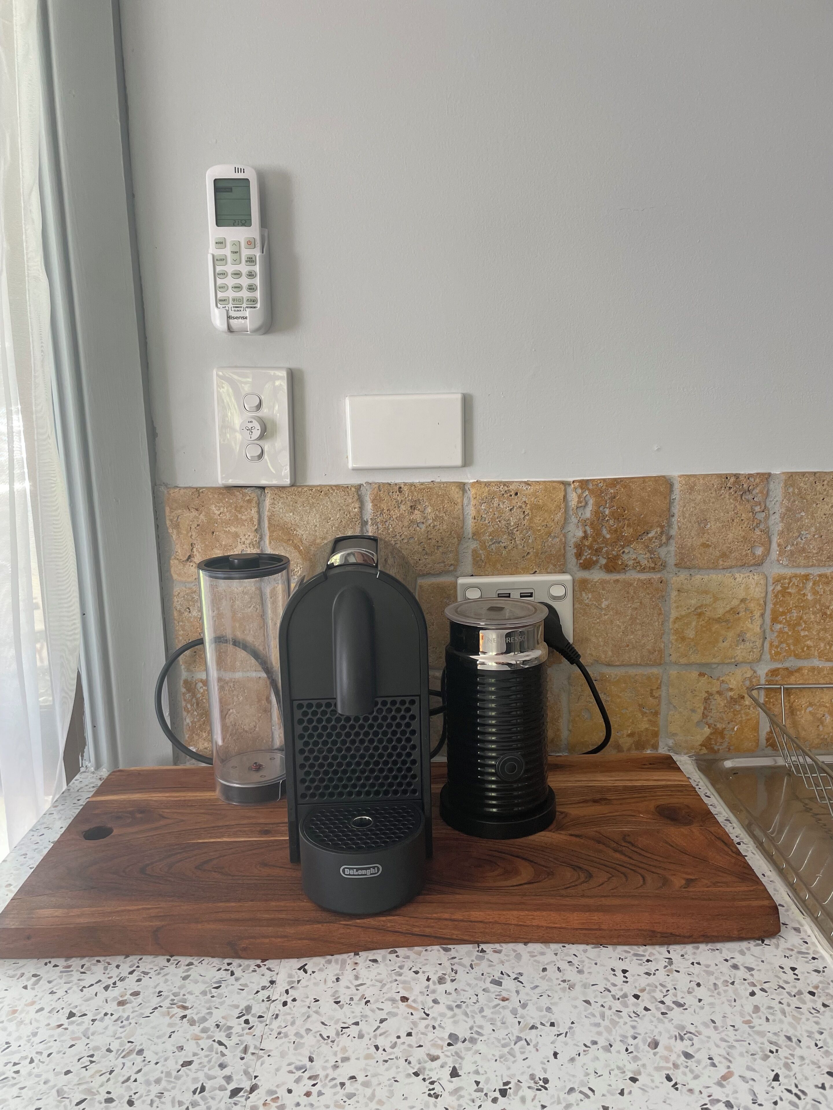 Eine Küchenzeile mit Kaffeemaschine, Wasserkocher und Telefon an einer Wandtafel.