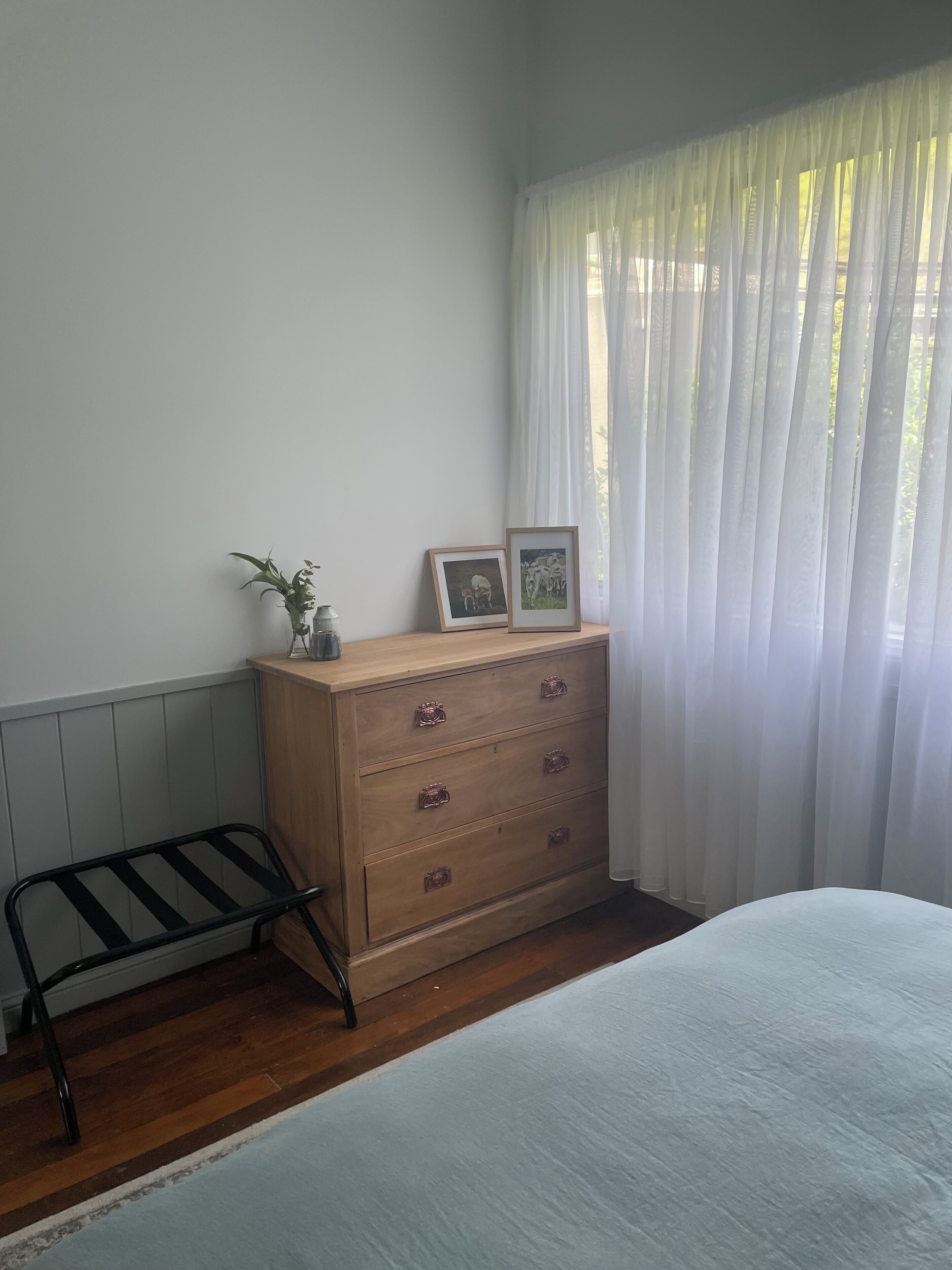 Une chambre à coucher avec une commode en bois, un banc en métal et un lit.