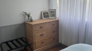 Une chambre à coucher avec une commode en bois, un banc en métal et un lit.