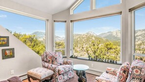 A room with large windows, patterned chairs, a round table, and a view of mountains. - Majestic views! 4 bedroom, 4.5 bath home close to town (Estes Park)