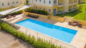 Un hotel con piscina, mobiliario exterior y un césped cuidado.