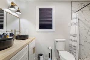 Features a sleek bathroom with a large mirror, dual sinks, and a contemporary toilet.