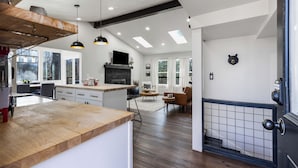 Una cocina moderna con encimera de madera, chimenea de piedra e iluminación empotrada.