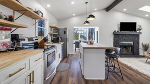 Una cocina moderna con estantes de madera, una isla central y una chimenea de piedra.