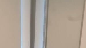 Una stanza con pavimento rivestito di moquette, una porta con stipite bianco e un interruttore a muro.