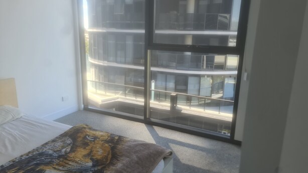 Una camera da letto con un'ampia finestra, un letto e un pavimento coperto di moquette.