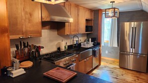 Una cocina moderna con armarios de madera, un refrigerador de acero inoxidable y una estufa a gas.